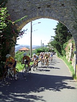 Sulla salita di Montemarcello i corridori transitano sotto il caratteristico arco romanico della Serra di Lerici