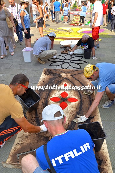 BRUGNATO (Infiorata del Corpus Domini 2015) - In via Riva d'Armi alcuni infioratori allestiscono disegni servendosi di sagome in legno e fondi di caff