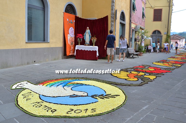 BRUGNATO (Infiorata del Corpus Domini 2015) - Colomba della pace nel logo di Via Roma. Sullo sfondo l'altare della Madonna dell'Olivo