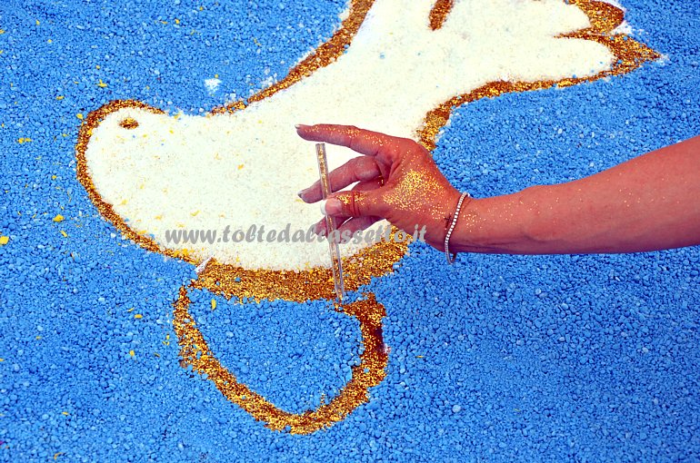 BRUGNATO (Infiorata del Corpus Domini 2015) - Un'infioratrice contorna il disegno di una colomba utilizzando dei brillantini dorati