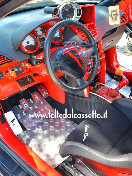 TUNING - Posto guida di una PEUGEOT 207 con interni di colore nero/rosso e pedaliere MOMO